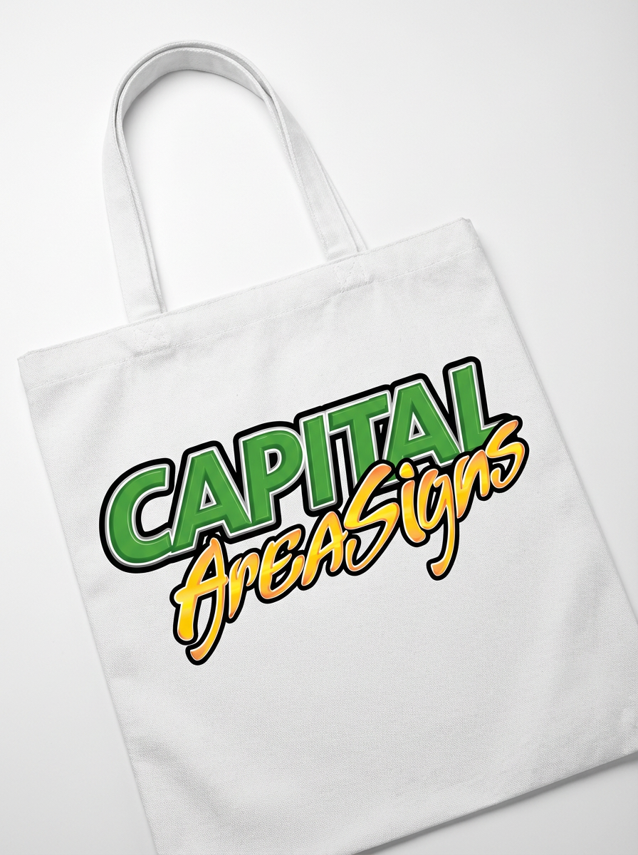 White canvas tote bag with DTF transfer logo displaying green gradient "CAPITAL" and orange gradient "AreaSigns" text, laid flat on white surface
